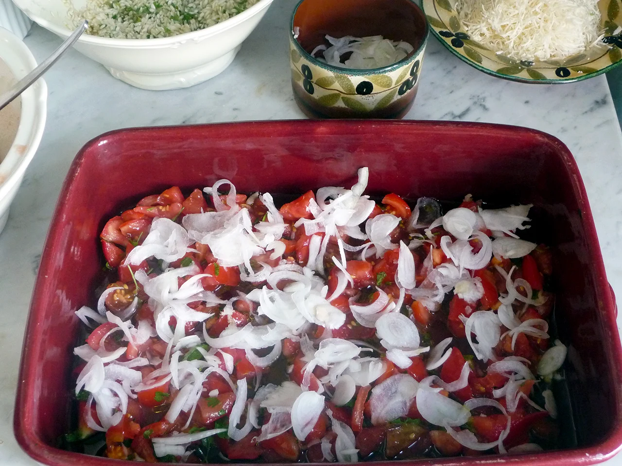 Montage du riso patate e cozze dans la tielle, première couche: huile d'olive, tomates, persil et oignons.